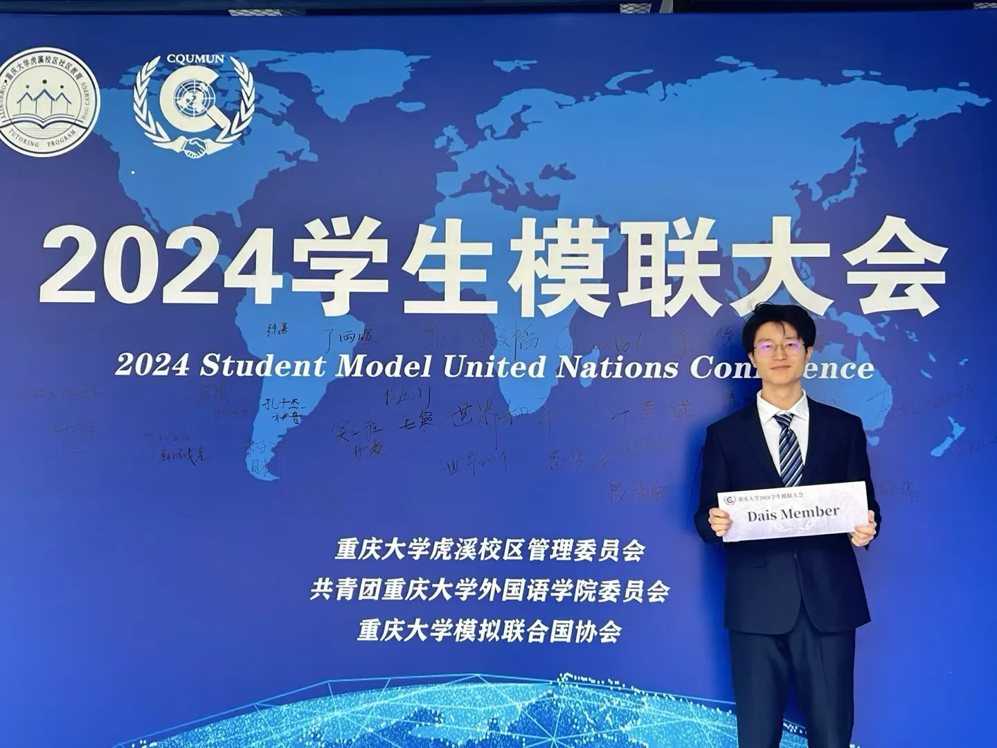 郭子谦在 2024 学生模拟联合国大会活动背景板前留影