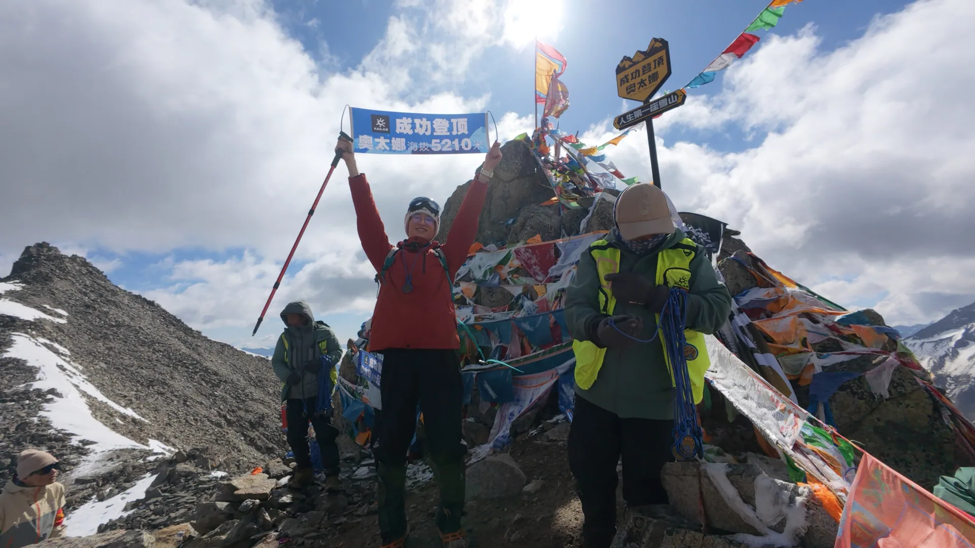 登山者在海拔5210米的奥太娜峰顶举起冰镐合影