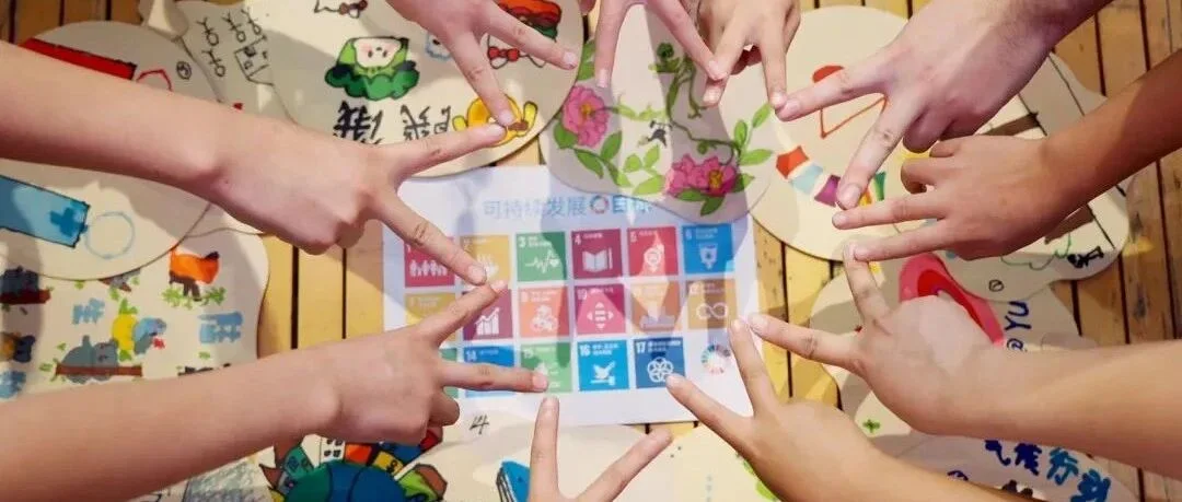 多双手围绕联合国可持续发展目标图案与学生绘画作品